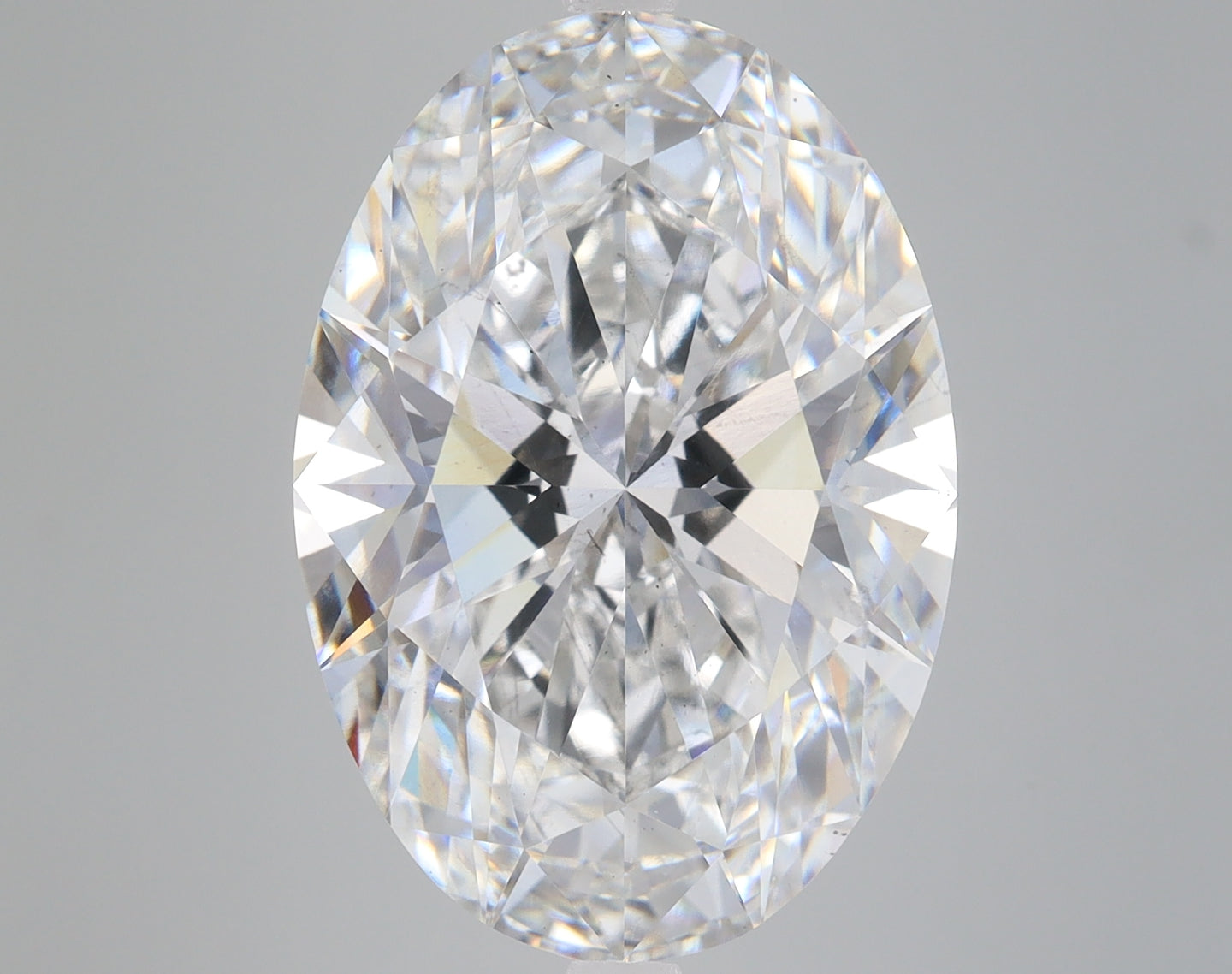 Oval-cut faceted diamond with clear transparency and light refraction on gray background.