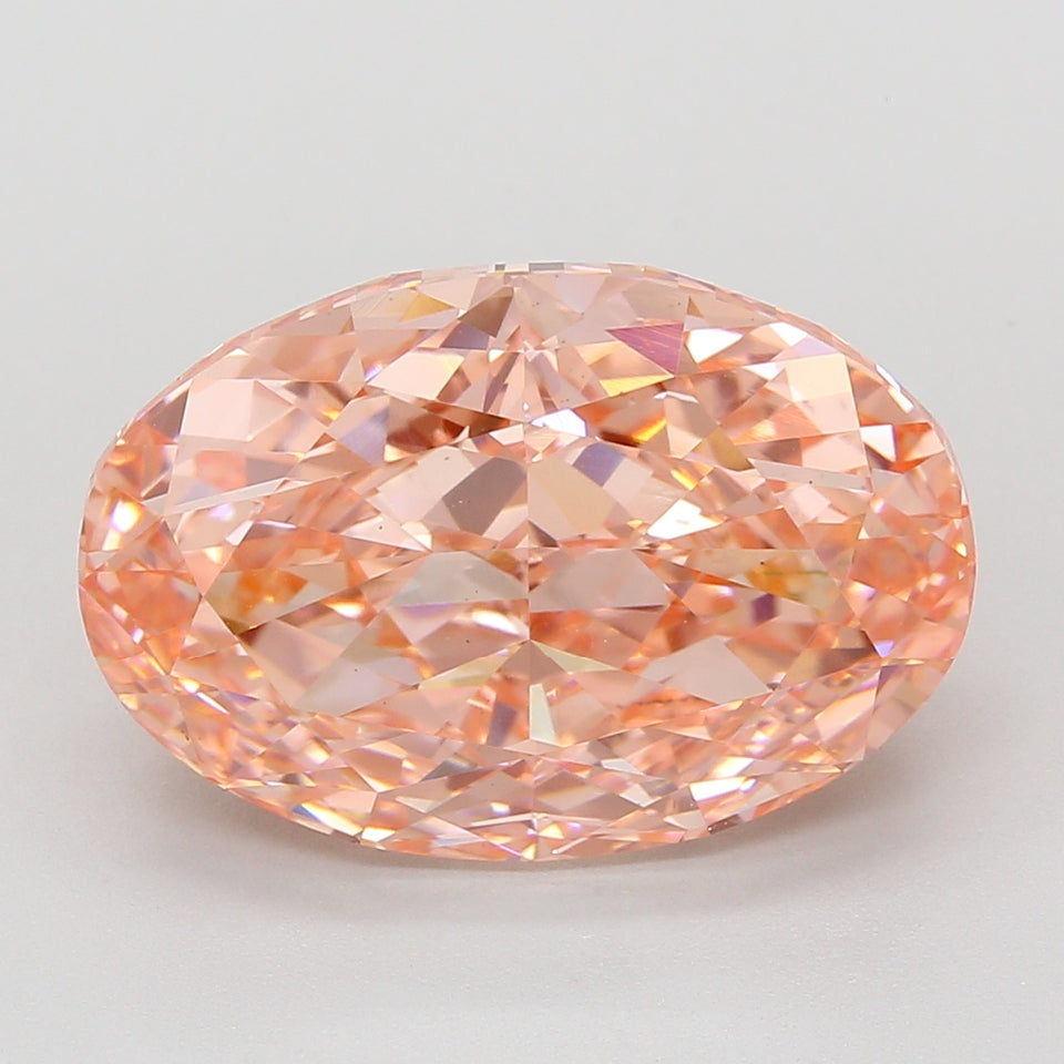 Oval lab-grown diamond with faceted cut and peachy-pink hue against neutral background.