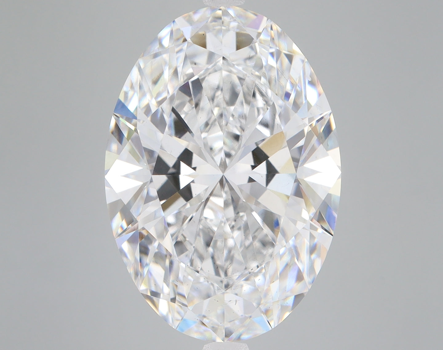 Oval-cut colorless lab-grown diamond with brilliant faceting and light refraction displayed against neutral background.