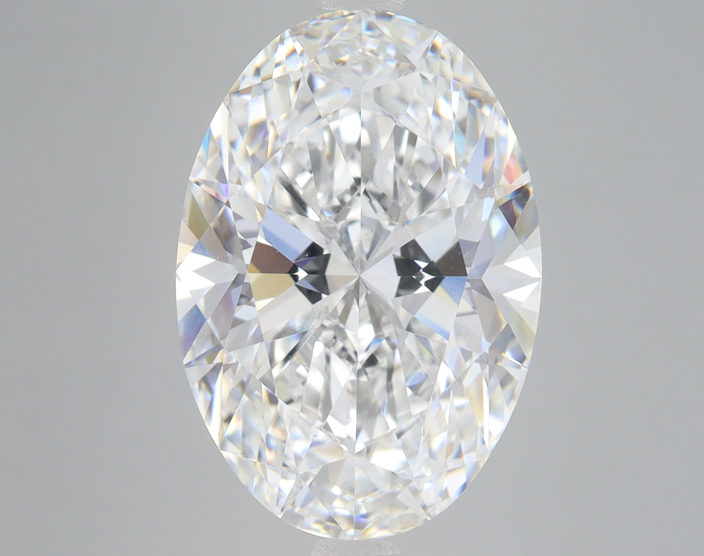 Oval-cut lab-grown diamond with faceted surface displaying light refraction on gray background.