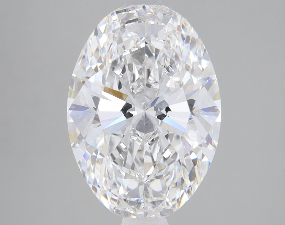 Clear oval-cut diamond with faceted surfaces reflecting light, displayed against neutral gray background.