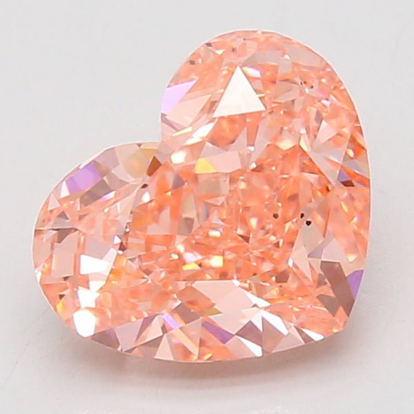 Heart-shaped lab-grown diamond with peachy-pink coloring and faceted surface, displayed against neutral background.