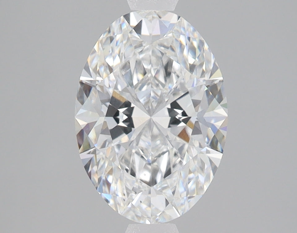 Oval-cut colorless lab-grown diamond with faceted surface reflecting light, displayed against neutral gray background.