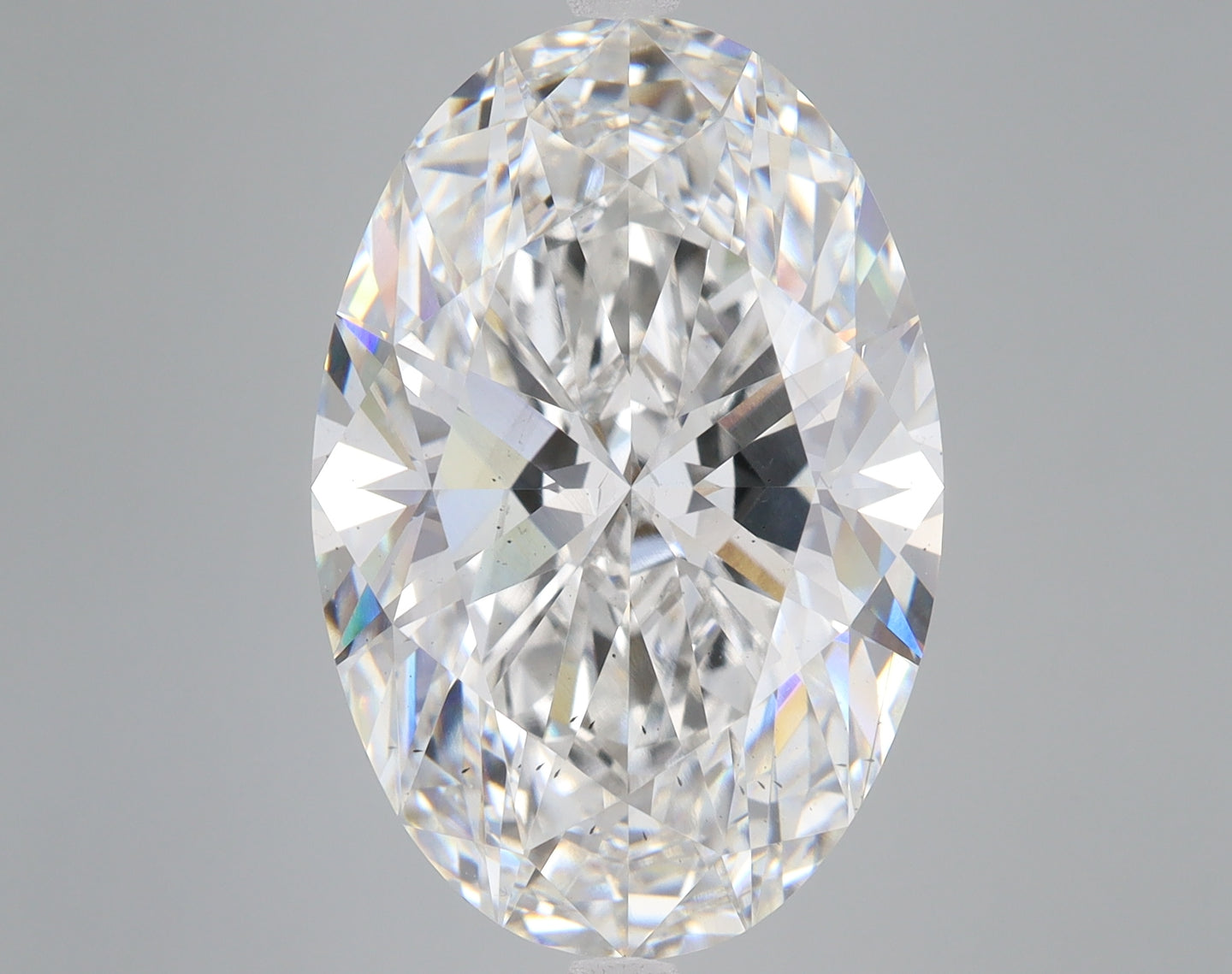 Oval-cut clear lab-grown diamond displaying faceted surfaces and light refraction against neutral background.