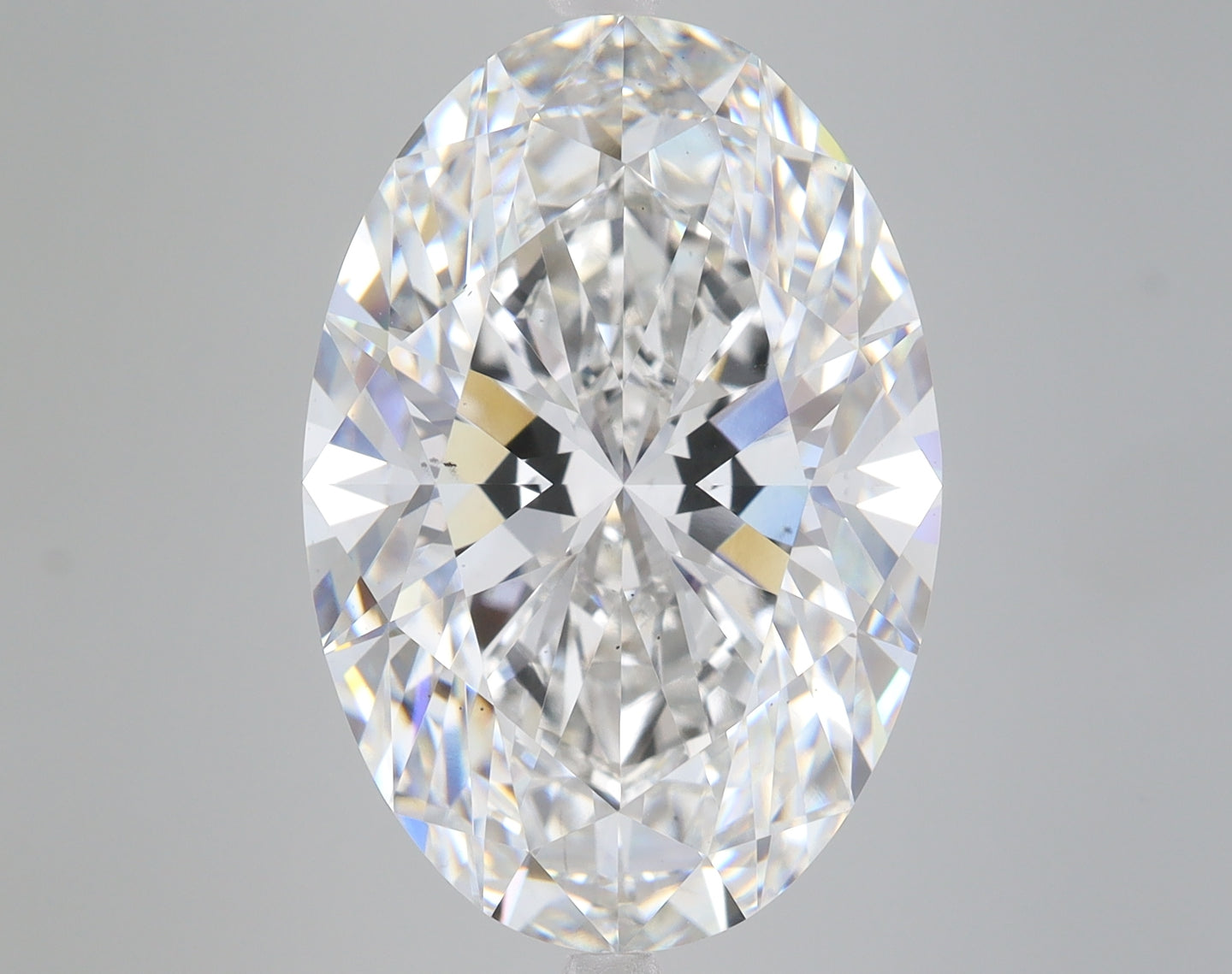 Oval-cut lab-grown diamond with faceted surface displaying colorless clarity and light refraction against gray background.