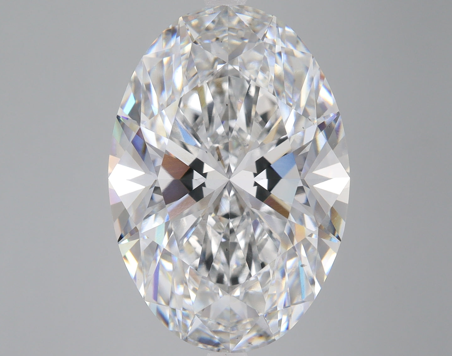 Colorless oval-cut lab-grown diamond with faceted surfaces reflecting light on neutral gray background.