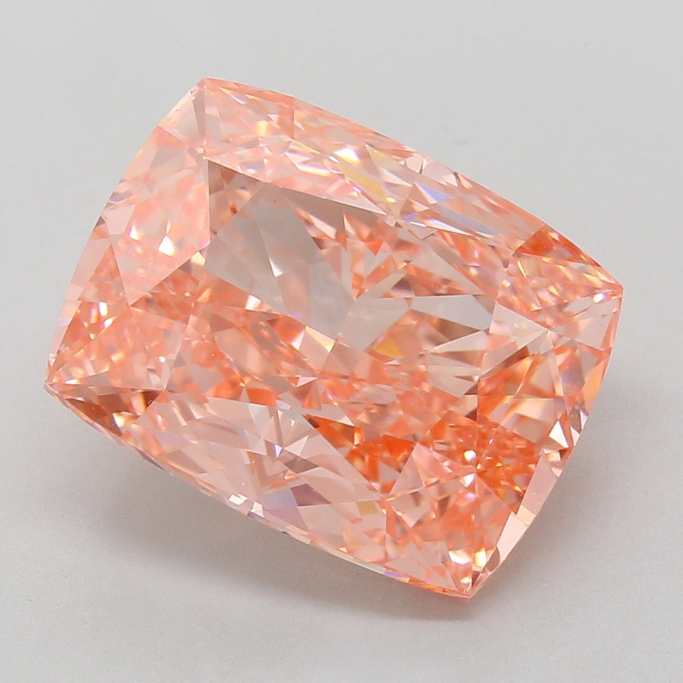 Cushion-cut lab-grown diamond with peachy-pink color and faceted surface showing light refraction.