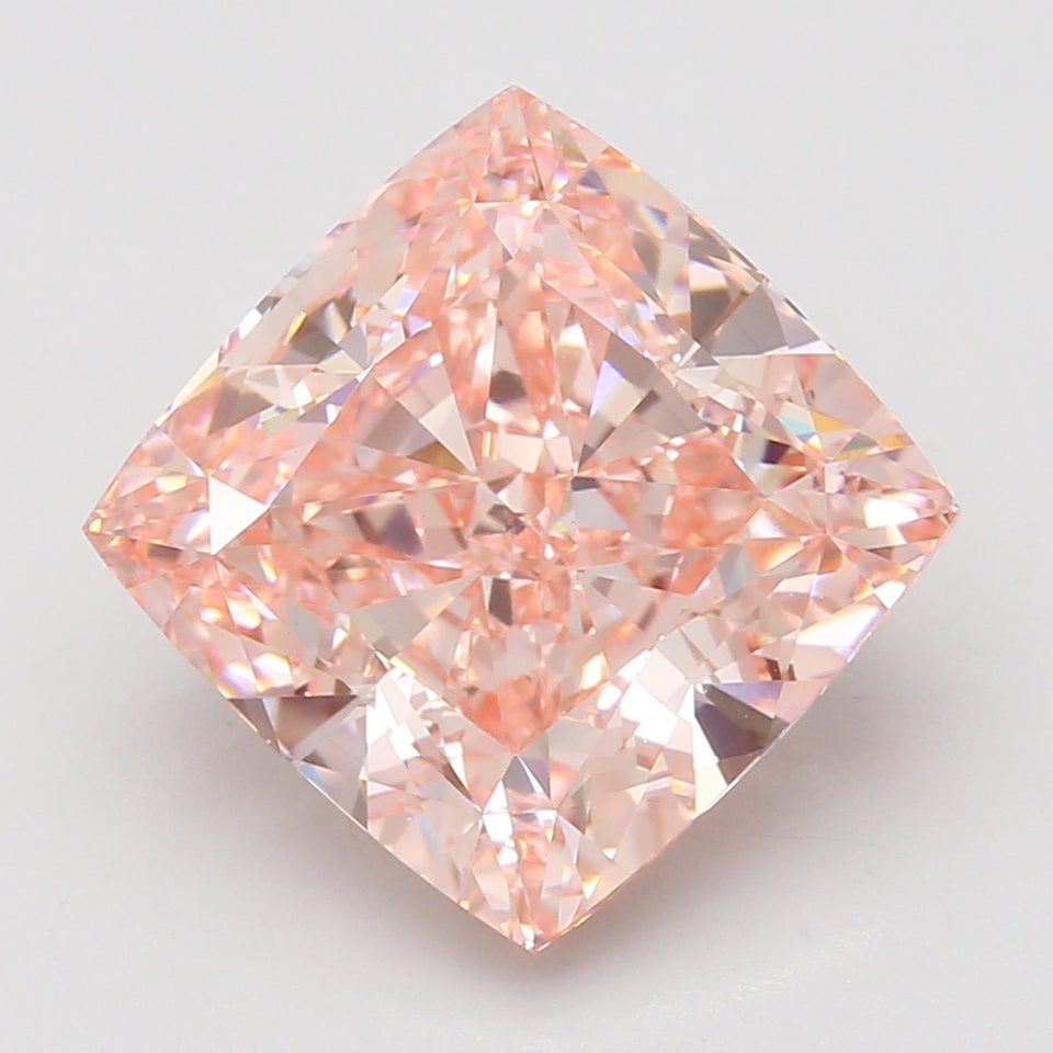 Cushion-cut lab-grown diamond with peachy-pink hue displaying faceted brilliance on neutral background.
