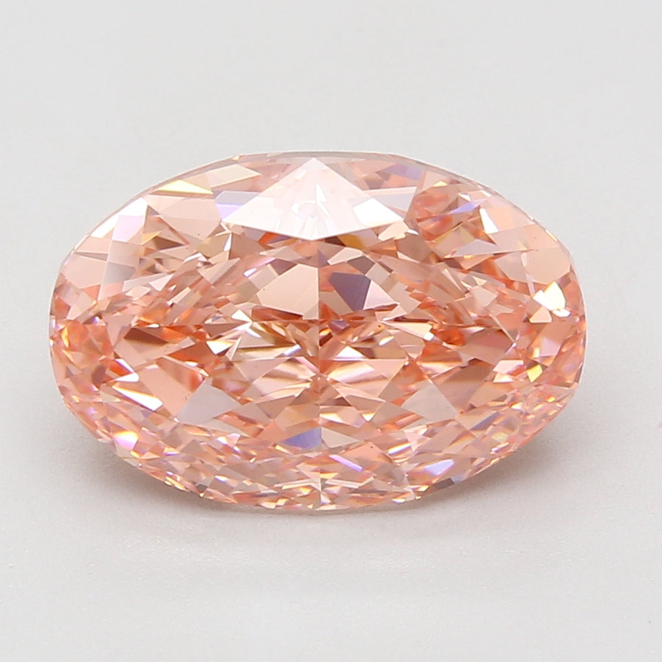 Oval-cut lab-grown diamond with peachy-pink coloring and faceted surface displaying light refraction.