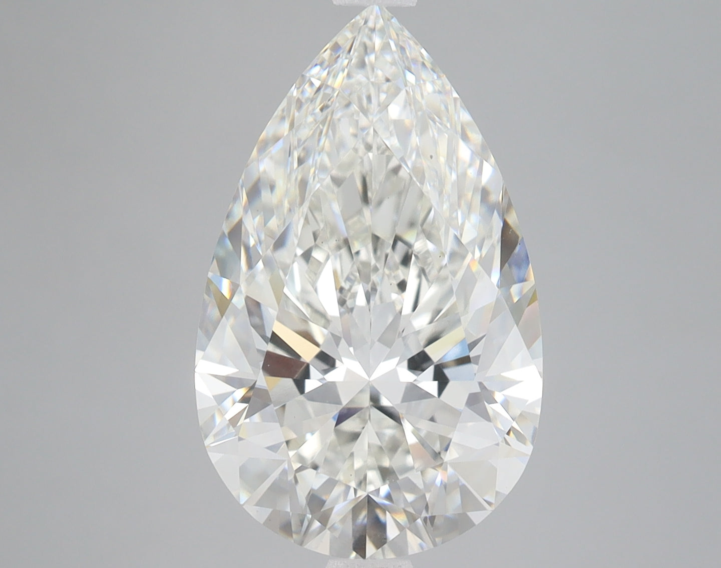 Pear-shaped colorless lab-grown diamond with faceted surface on gray background.