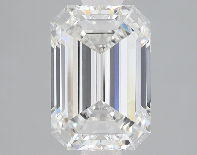 Colorless emerald-cut lab-grown diamond with faceted surfaces and light refraction, displayed against neutral background.
