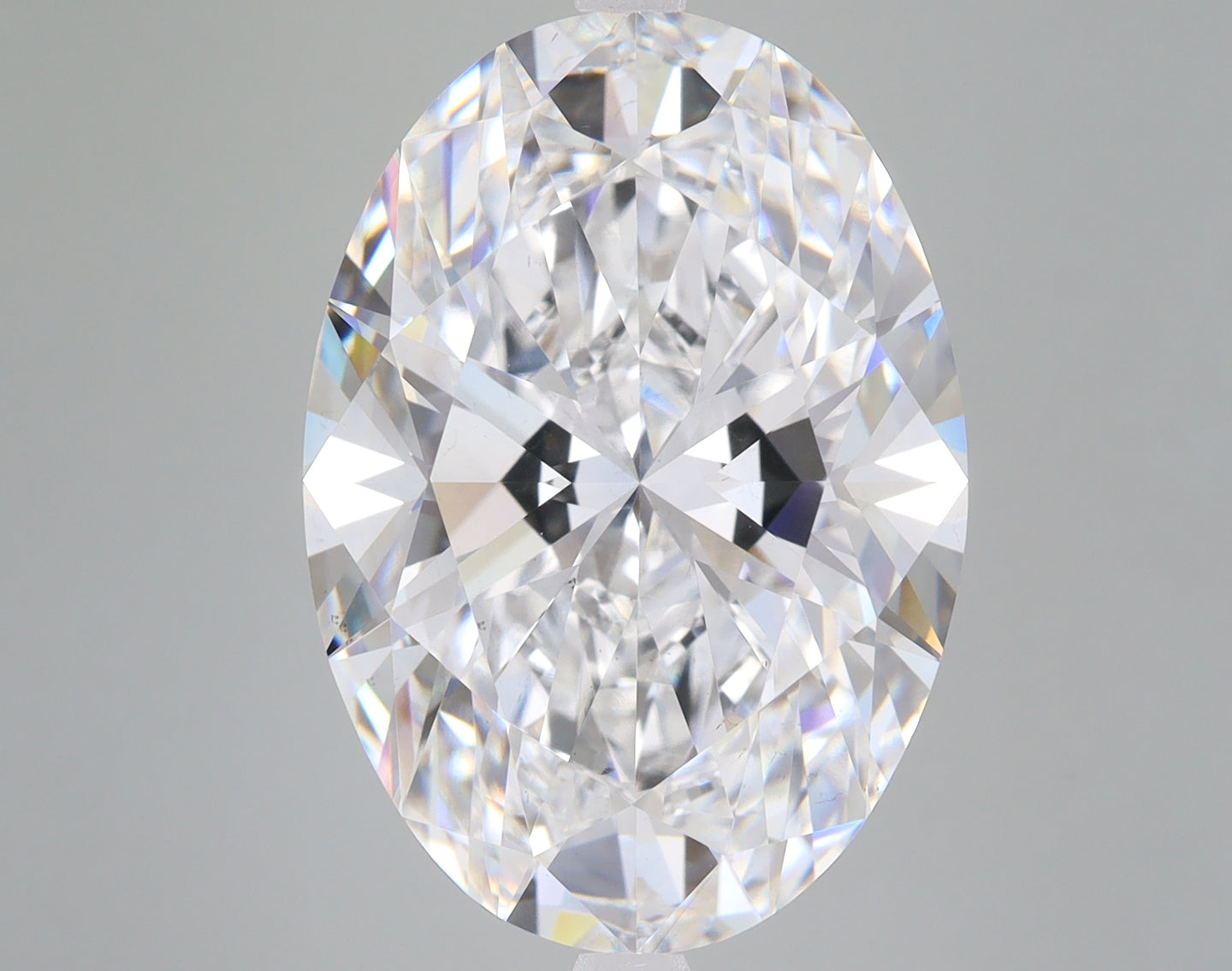 Oval-cut lab-grown diamond with faceted surface displaying white and prismatic light reflections.