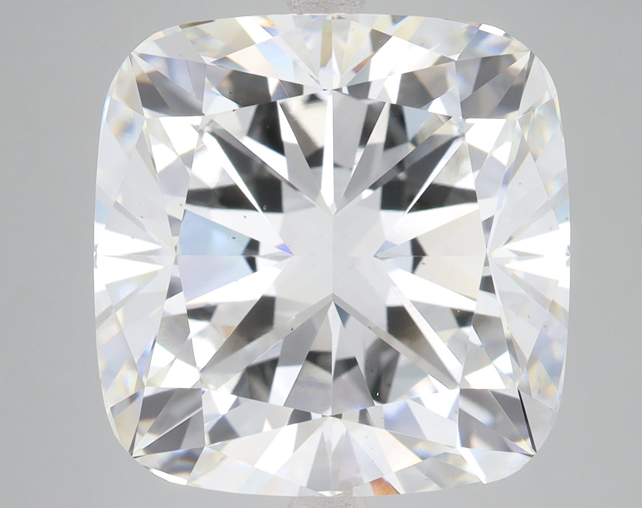 Cushion cut loose diamond with faceted surface reflecting light, displayed against neutral gray background.