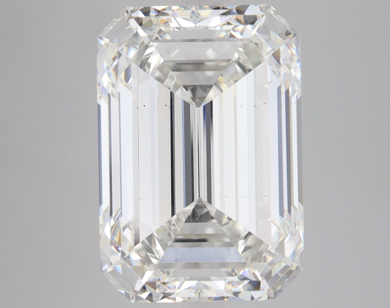 Emerald-cut lab-grown diamond with faceted sides and stepped pavilion, displaying light refraction and clarity against gray b