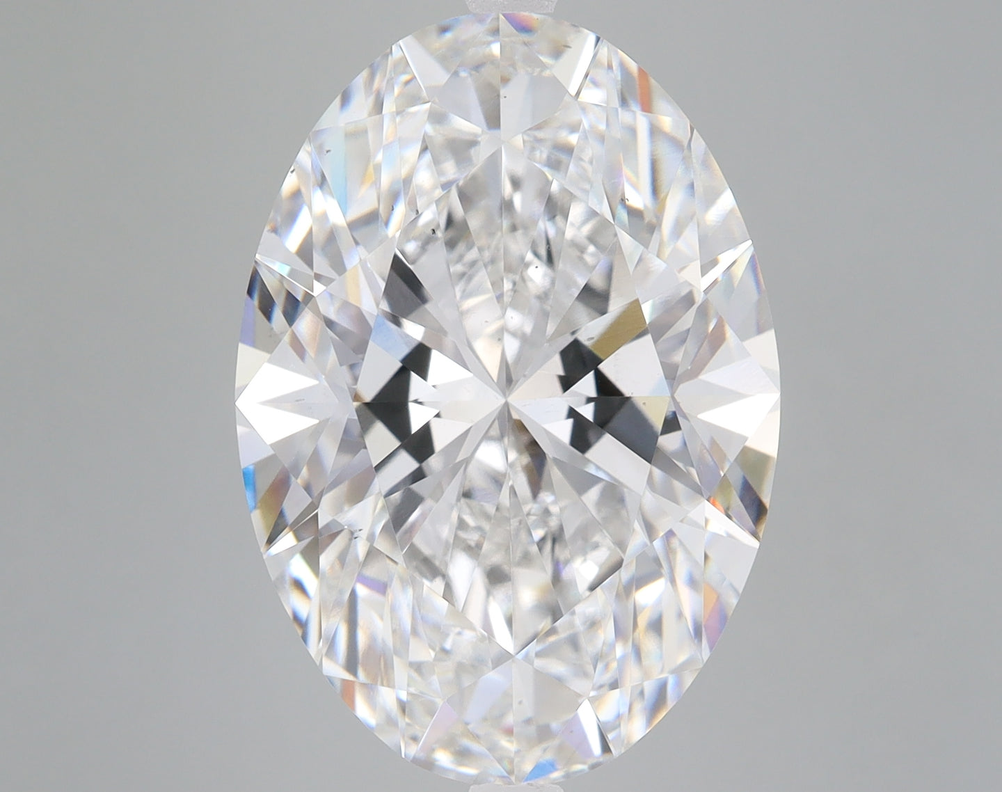 Oval-cut colorless lab-grown diamond with faceted surface and light refraction displayed against gray background.