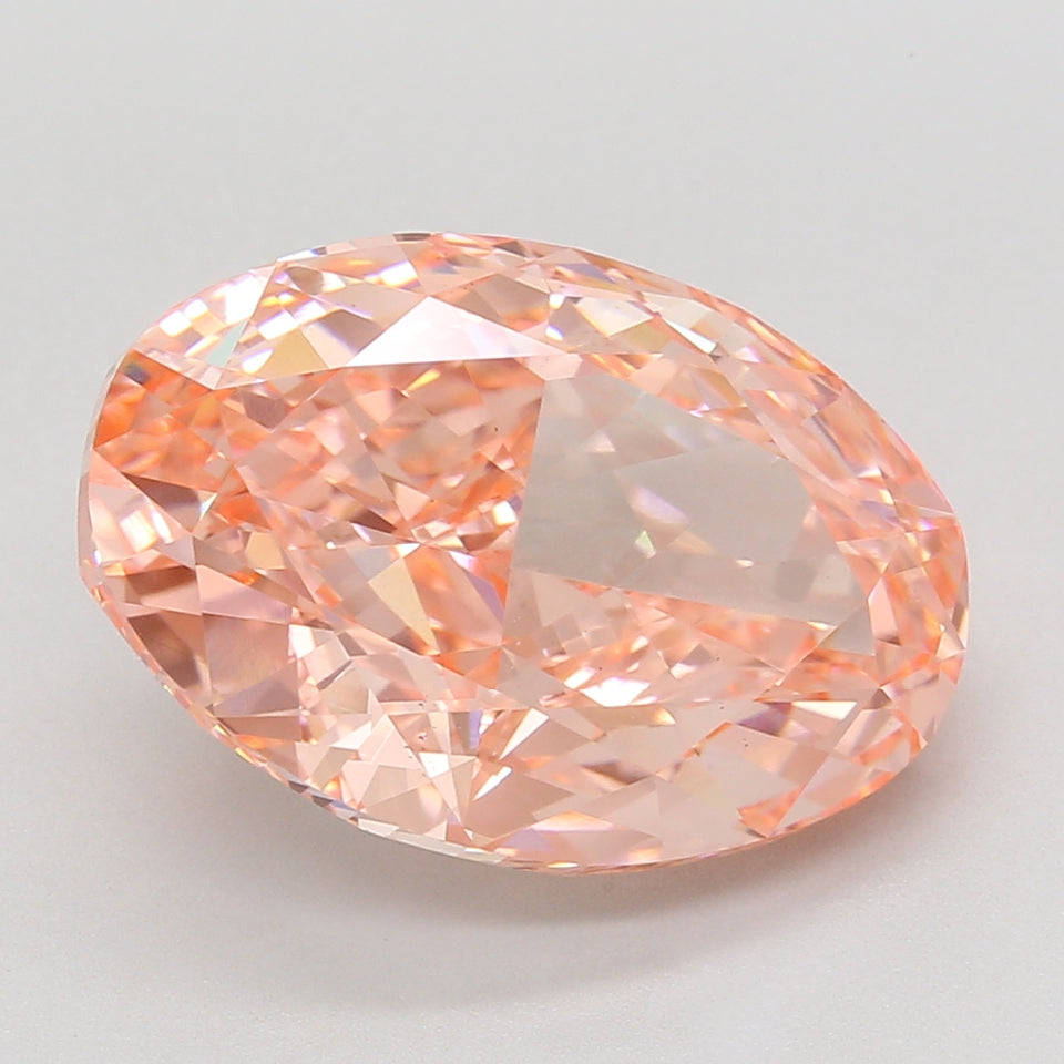 Oval-cut lab-grown diamond with peach-pink hue and faceted surface, displayed against neutral background.