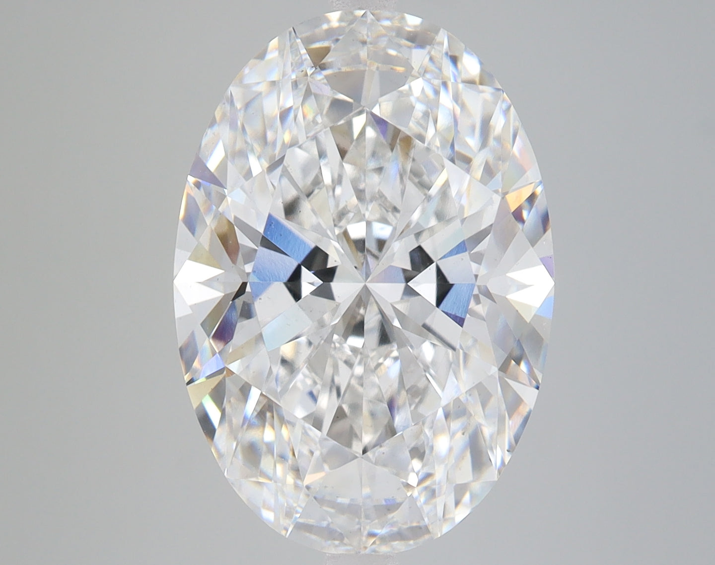 Oval-cut lab-grown diamond with faceted surface displaying light refraction and colorless transparency against neutral backgr