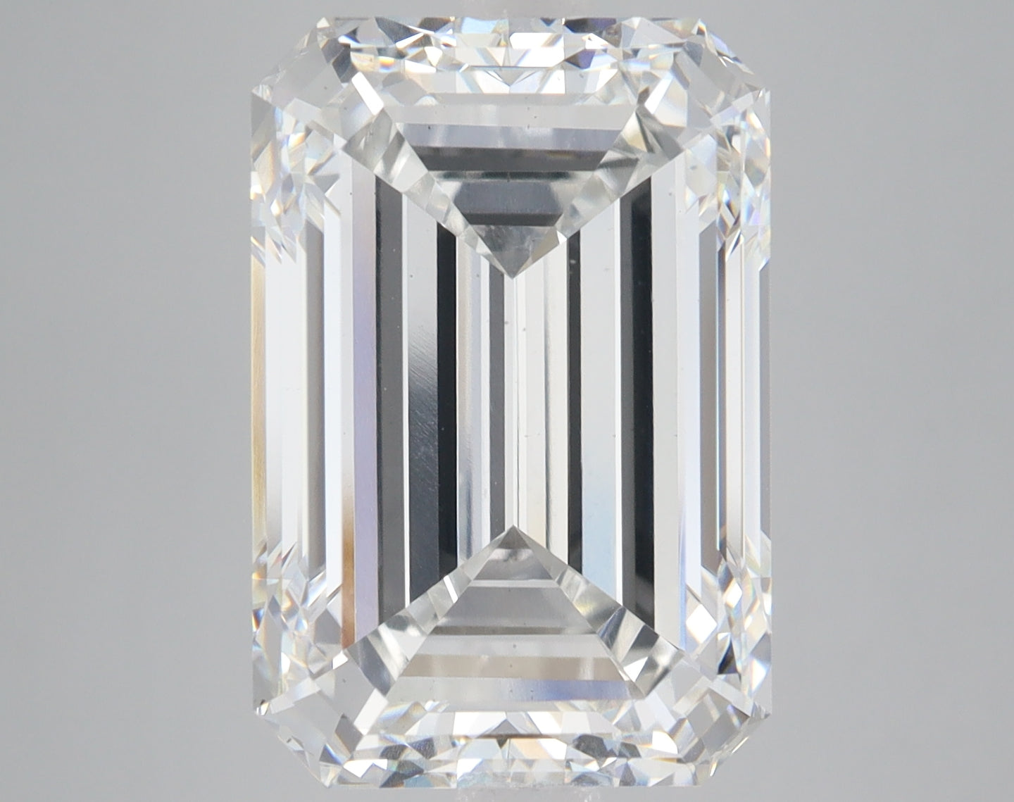 Emerald-cut lab-grown diamond with clear faceting and light reflection on neutral gray background.
